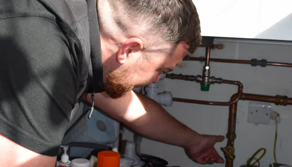 A Gas Safe Plumber fixing pipes under a sink